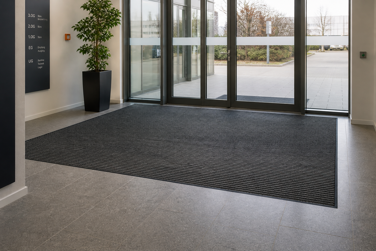 Haltbare Sauberlaufmatte in dunkelgrau im Eingangsbereich eines Bürogebäudes zur Schmutzaufnahme.